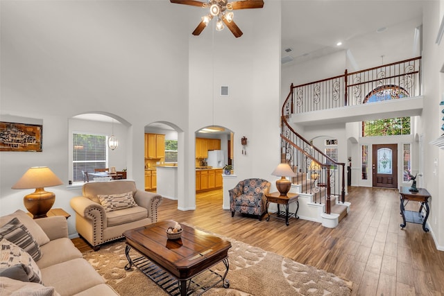 6406 Pine Reserve Dr, Spring, TX 77389 - living room featuring ceiling fan, arched walkways, light wood finished floors, a towering ceiling, and stairway