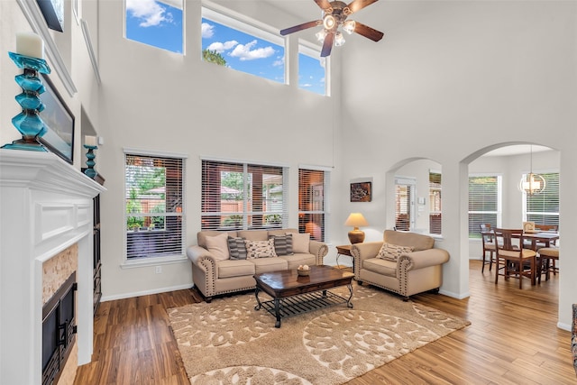 6406 Pine Reserve Dr, Spring, TX 77389 - living room featuring ceiling fan, a fireplace, arched walkways, a towering ceiling, and healthy amount of natural light
