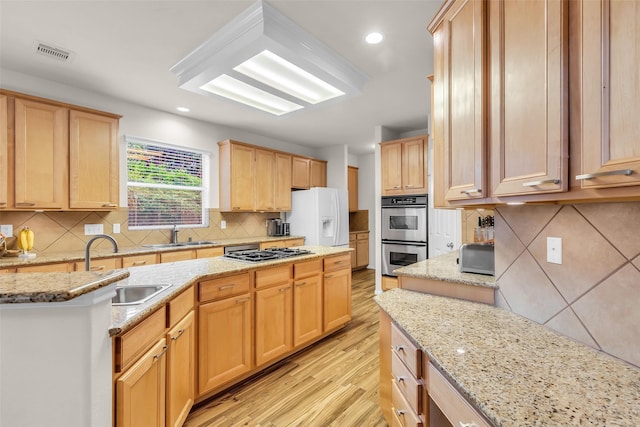 6406 Pine Reserve Dr, Spring, TX 77389 - kitchen featuring appliances with stainless steel finishes, backsplash, light wood-style flooring, light brown cabinets, and light stone countertops