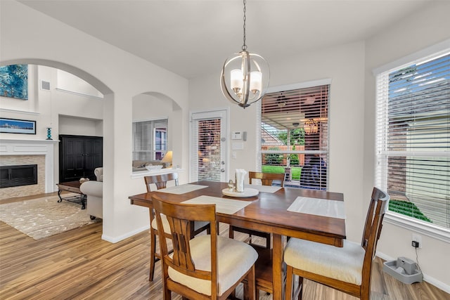6406 Pine Reserve Dr, Spring, TX 77389 - dining area with light wood-style floors, a chandelier, arched walkways, and a premium fireplace