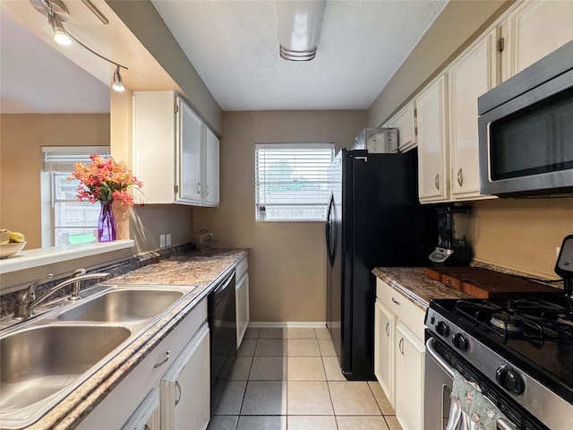 720 E Murray St, Angleton, TX 77515 - kitchen featuring stainless steel appliances, a sink, baseboards, white cabinets, and light tile patterned flooring