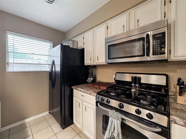 720 E Murray St, Angleton, TX 77515 - kitchen featuring stainless steel appliances, white cabinets, light tile patterned floors, baseboards, and dark countertops