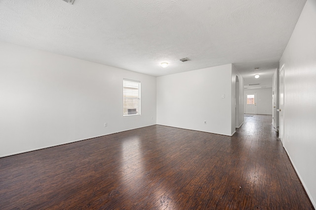 19130 Yaupon Ranch Dr, Cypress, TX 77433 - unfurnished room featuring healthy amount of natural light, dark wood-style flooring, a textured ceiling, arched walkways, and baseboards
