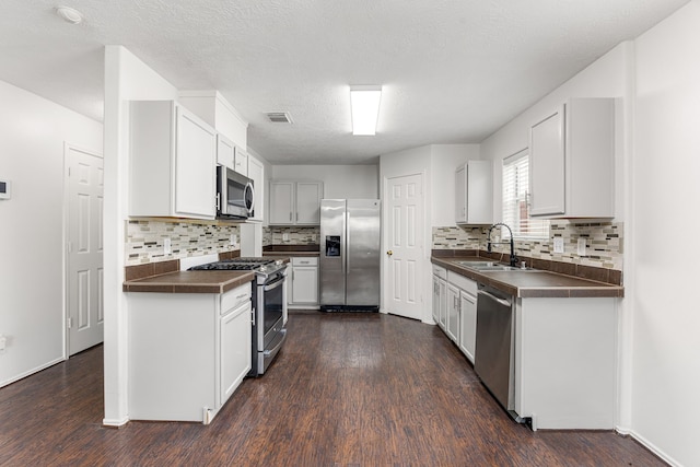19130 Yaupon Ranch Dr, Cypress, TX 77433 - kitchen featuring stainless steel appliances, dark countertops, a sink, and dark wood-style flooring