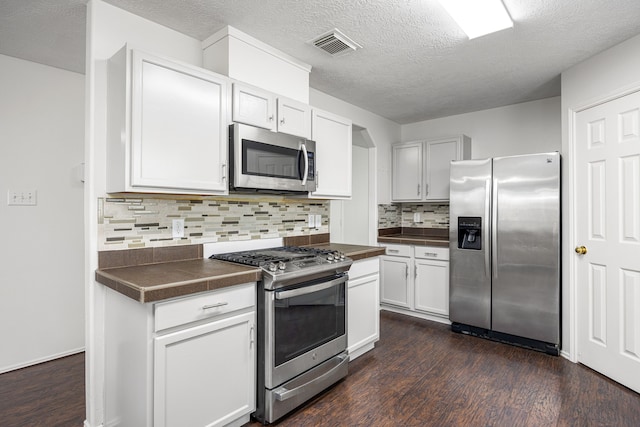 19130 Yaupon Ranch Dr, Cypress, TX 77433 - kitchen featuring appliances with stainless steel finishes, dark countertops, dark wood-style floors, and a textured ceiling