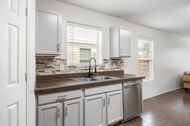 19130 Yaupon Ranch Dr, Cypress, TX 77433 - kitchen featuring a sink, stainless steel dishwasher, dark countertops, backsplash, and dark wood finished floors