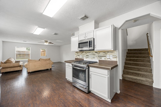 19130 Yaupon Ranch Dr, Cypress, TX 77433 - kitchen featuring stainless steel appliances, dark countertops, decorative backsplash, dark wood-type flooring, and a textured ceiling
