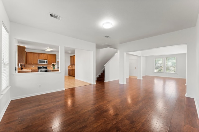 235 Doncaster St, Conroe, TX 77303 - unfurnished living room with a sink, stairs, wood finished floors, and baseboards