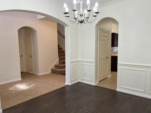 20314 Paso Fino Dr, Humble, TX 77338 - spare room featuring dark wood-style floors, crown molding, a chandelier, stairs, and wainscoting