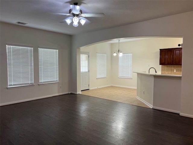 20314 Paso Fino Dr, Humble, TX 77338 - unfurnished living room featuring a chandelier, arched walkways, a ceiling fan, wood finished floors, and baseboards