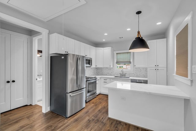 501 Avondale St, Houston, TX 77006 - kitchen with appliances with stainless steel finishes, a sink, a peninsula, white cabinets, and recessed lighting