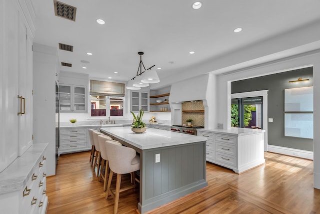 501 Avondale St, Houston, TX 77006 - kitchen featuring a center island, white cabinetry, open shelves, stove, and a sink