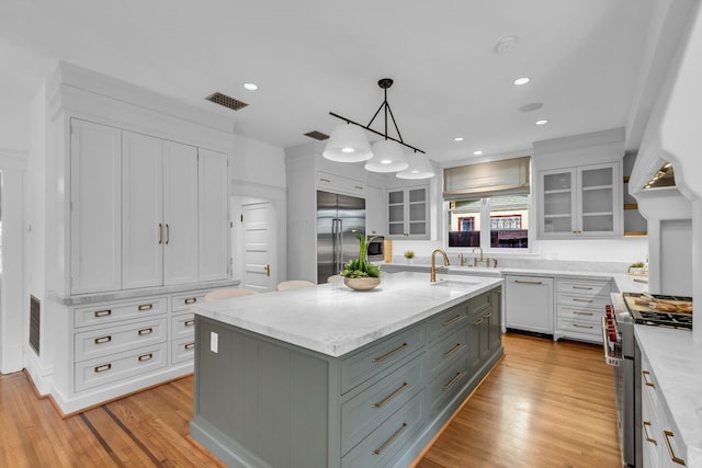 501 Avondale St, Houston, TX 77006 - kitchen featuring high quality appliances, a sink, white cabinets, an island with sink, and recessed lighting