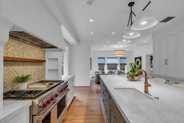 501 Avondale St, Houston, TX 77006 - kitchen featuring range with two ovens, a sink, recessed lighting, white cabinets, and tasteful backsplash