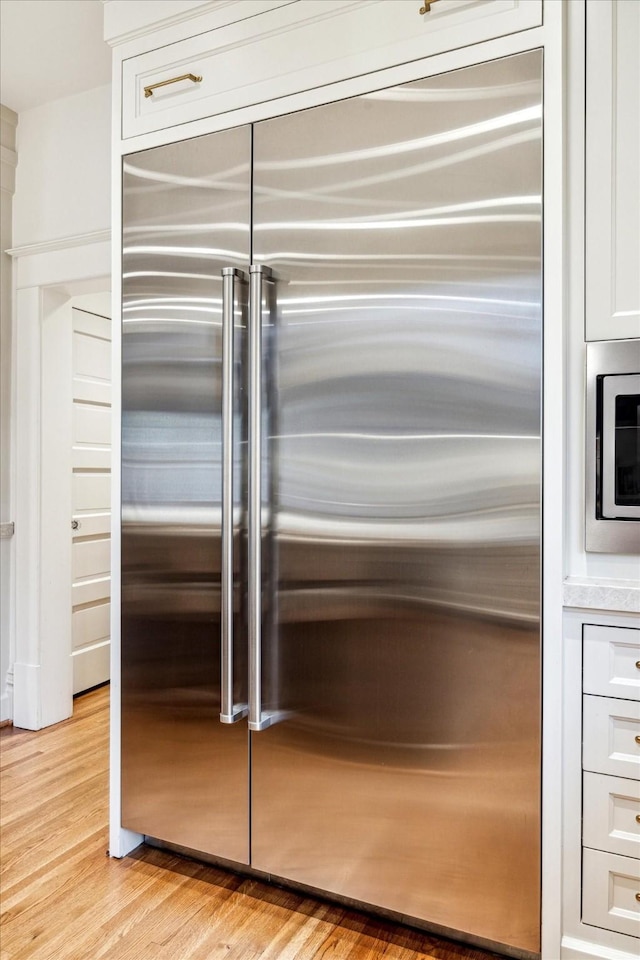 501 Avondale St, Houston, TX 77006 - kitchen view of built in appliances, white cabinets, light wood-type flooring, and light countertops