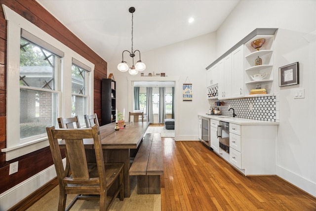 1128 W Temple St, Houston, TX 77009 - dining room with wine cooler, a chandelier, hardwood / wood-style floors, baseboards, and vaulted ceiling