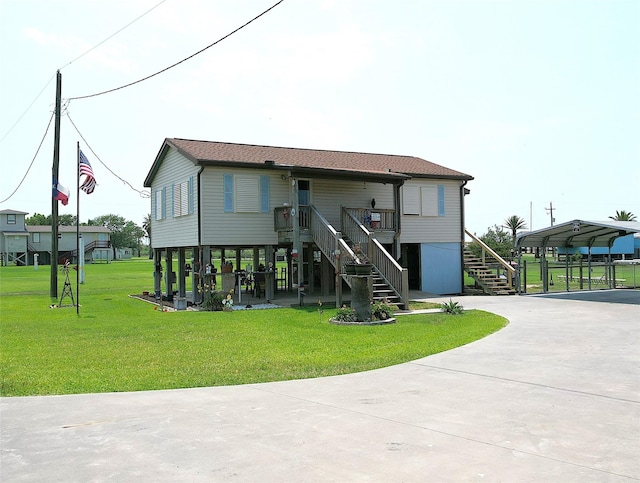 1321 Pickney Ave, Port Bolivar, TX 77650 - back of house featuring stairway, driveway, a lawn, and a carport