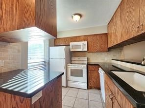 1205 Autrey St Unit 11, Houston, TX 77006 - kitchen with white appliances, dark countertops, and brown cabinetry