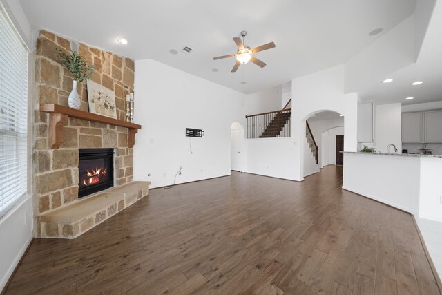 18719 Big Elm Dr, Cypress, TX 77433 - unfurnished living room featuring arched walkways, ceiling fan, dark wood finished floors, a stone fireplace, and recessed lighting