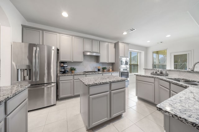 18719 Big Elm Dr, Cypress, TX 77433 - kitchen featuring stainless steel appliances, gray cabinetry, a sink, under cabinet range hood, and a center island