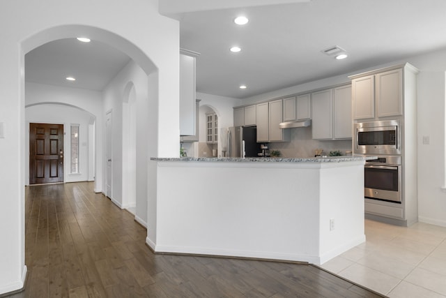 18719 Big Elm Dr, Cypress, TX 77433 - kitchen with stainless steel appliances, light stone countertops, backsplash, under cabinet range hood, and gray cabinets