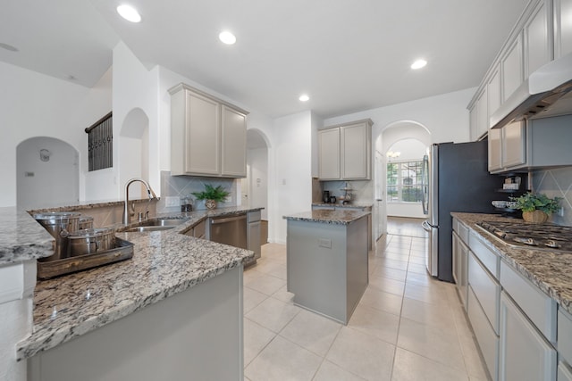 18719 Big Elm Dr, Cypress, TX 77433 - kitchen with arched walkways, a sink, appliances with stainless steel finishes, under cabinet range hood, and recessed lighting