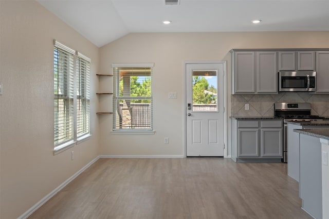 323 Jewett Meadow Dr, Magnolia, TX 77354 - kitchen with stainless steel appliances, gray cabinets, light wood finished floors, tasteful backsplash, and vaulted ceiling