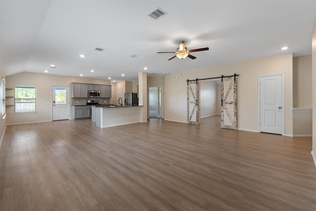 323 Jewett Meadow Dr, Magnolia, TX 77354 - unfurnished living room featuring a sink, ceiling fan, a barn door, light wood finished floors, and baseboards