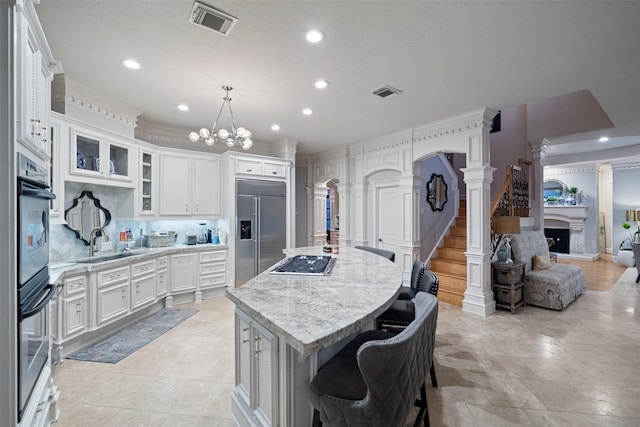 11 Hope Valley Pl, The Woodlands, TX 77382 - kitchen featuring appliances with stainless steel finishes, a fireplace with raised hearth, a chandelier, a sink, and recessed lighting
