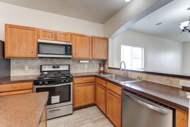 20515 Sycamore Crest Ln, Katy, TX 77449 - kitchen featuring stainless steel appliances, a sink, decorative backsplash, light wood finished floors, and dark countertops