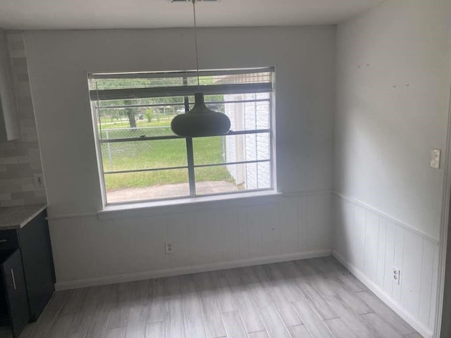 30714 Meadow Wood Dr, Magnolia, TX 77354 - unfurnished dining area featuring light wood-type flooring, healthy amount of natural light, and wainscoting