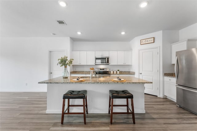 992 Blue Beech Ln, Brookshire, TX 77423 - kitchen featuring stainless steel appliances, stone countertops, a kitchen bar, wood finished floors, and recessed lighting