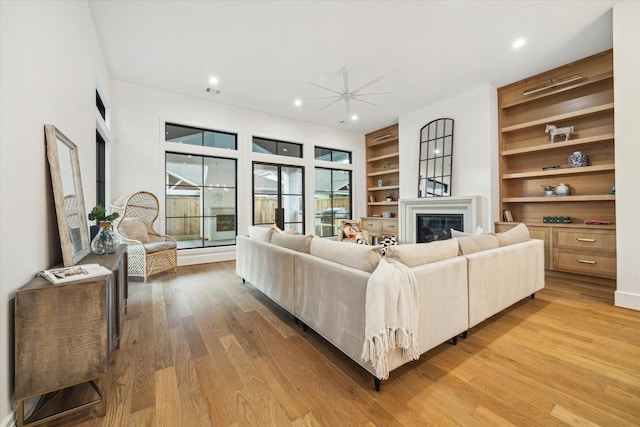 1314 Richelieu Ln, Houston, TX 77018 - living room with ceiling fan, a glass covered fireplace, built in shelves, light wood-style floors, and recessed lighting