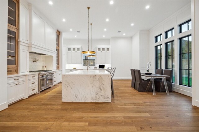 1314 Richelieu Ln, Houston, TX 77018 - kitchen featuring double oven range, a center island with sink, backsplash, white cabinets, and recessed lighting