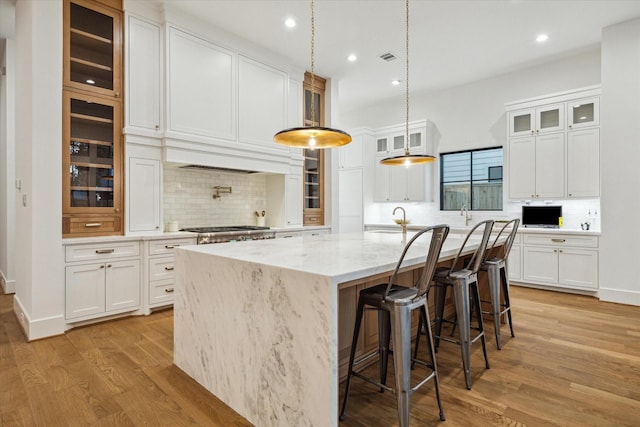 1314 Richelieu Ln, Houston, TX 77018 - kitchen with decorative backsplash, light wood finished floors, a large island, white cabinetry, and recessed lighting
