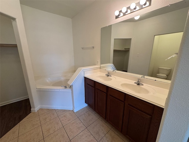 914 Paradise Rd, Baytown, TX 77521 - bathroom with double vanity, tile patterned floors, a bath, a walk in closet, and toilet