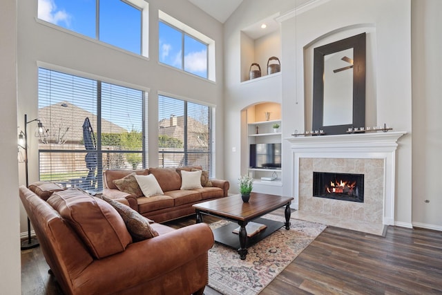 18430 S Settlers Shore Dr, Cypress, TX 77433 - living area featuring built in shelves, wood finished floors, a towering ceiling, a fireplace, and baseboards