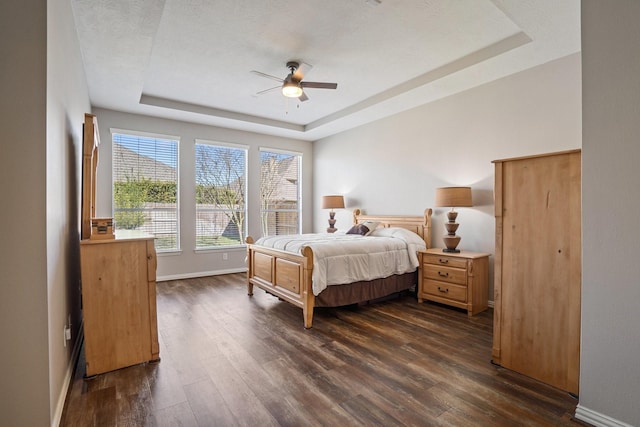18430 S Settlers Shore Dr, Cypress, TX 77433 - bedroom with a tray ceiling, dark wood-type flooring, baseboards, and ceiling fan