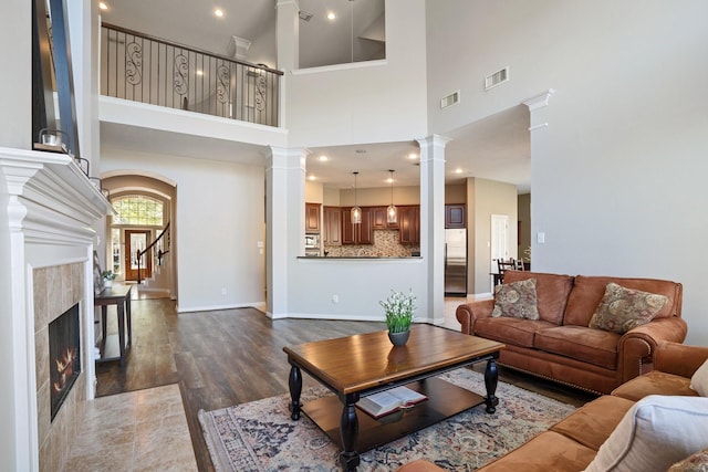 18430 S Settlers Shore Dr, Cypress, TX 77433 - living room featuring ornate columns, wood finished floors, a towering ceiling, a fireplace, and baseboards