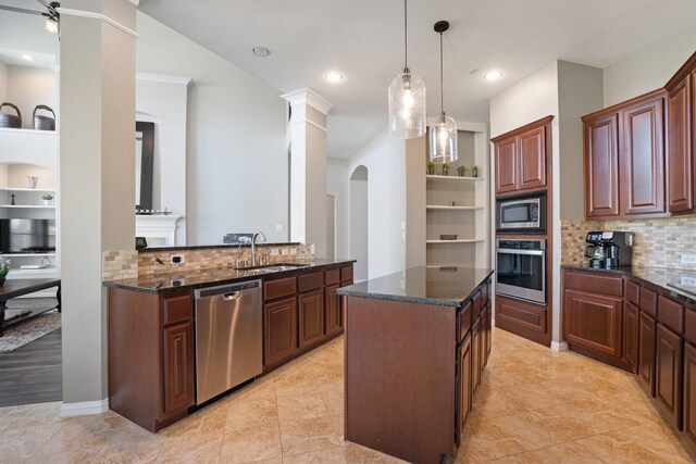 18430 S Settlers Shore Dr, Cypress, TX 77433 - kitchen featuring stainless steel appliances, a sink, arched walkways, tasteful backsplash, and a kitchen island