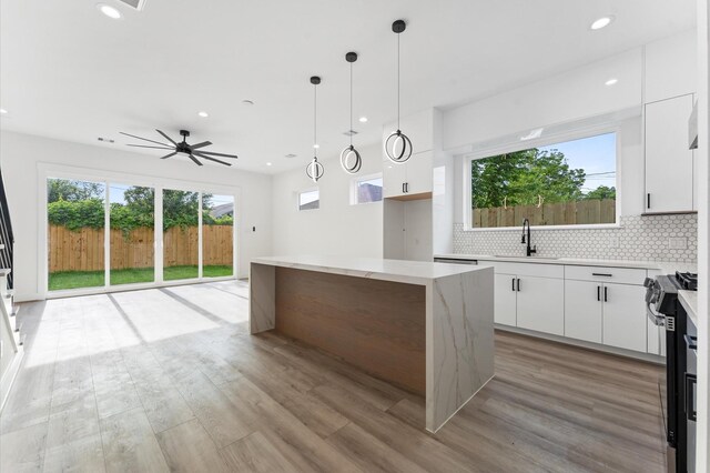 503 Nimrod St, Houston, TX 77020 - kitchen with stainless steel gas range, a sink, white cabinets, light wood finished floors, and recessed lighting