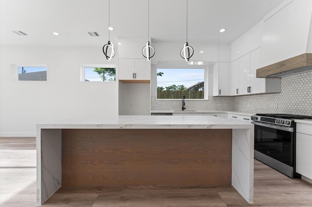 503 Nimrod St, Houston, TX 77020 - kitchen with premium range hood, stainless steel electric stove, white cabinetry, decorative backsplash, and a kitchen island