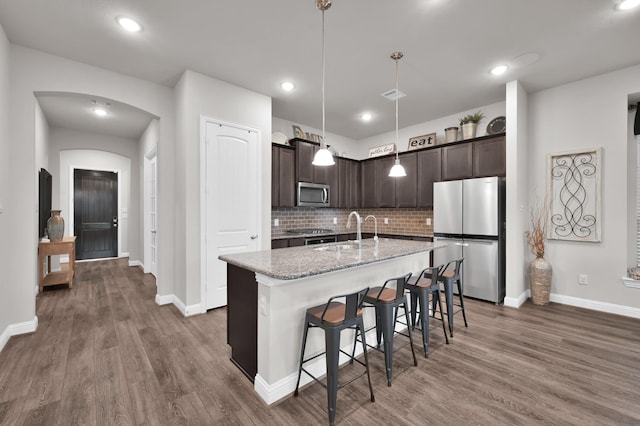 17413 Turtleweed Ln, Conroe, TX 77385 - kitchen featuring stainless steel appliances, dark brown cabinetry, arched walkways, dark wood-style flooring, and recessed lighting