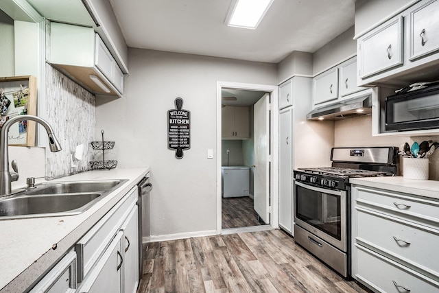 204 Carnation St, Lake Jackson, TX 77566 - kitchen featuring appliances with stainless steel finishes, under cabinet range hood, a sink, light wood-style flooring, and light countertops