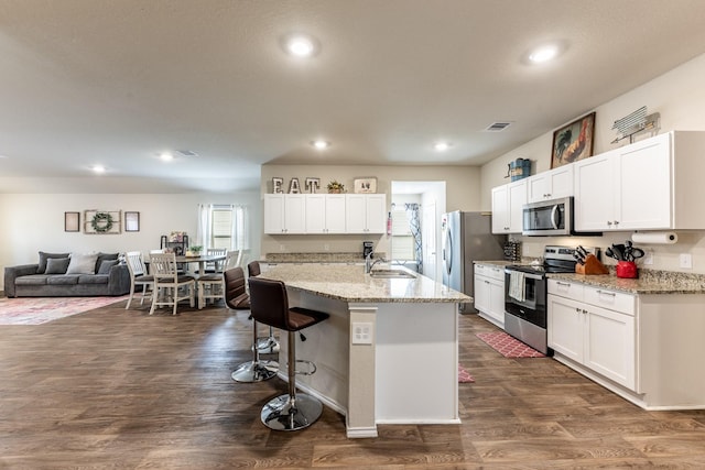128 Barton Creek Dr, Huntsville, TX 77340 - kitchen featuring appliances with stainless steel finishes, a breakfast bar, dark wood-style floors, white cabinetry, and a sink