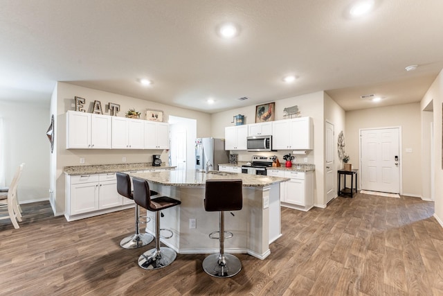 128 Barton Creek Dr, Huntsville, TX 77340 - kitchen with stainless steel appliances, wood finished floors, a breakfast bar, a kitchen island with sink, and recessed lighting