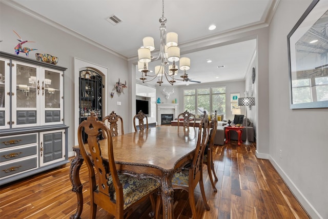 3909 Rose St, Houston, TX 77007 - dining room with dark wood finished floors, a chandelier, a glass covered fireplace, crown molding, and baseboards
