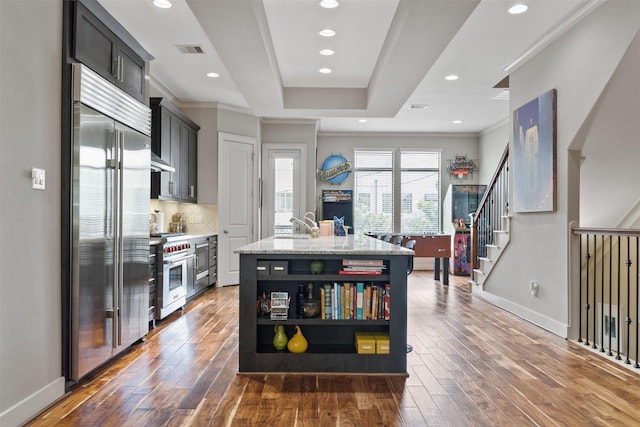 3909 Rose St, Houston, TX 77007 - kitchen with high quality appliances, dark wood-style floors, an island with sink, tasteful backsplash, and recessed lighting