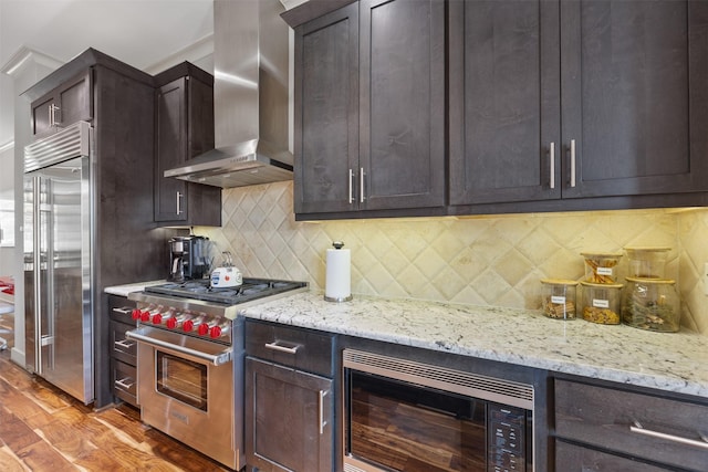 3909 Rose St, Houston, TX 77007 - kitchen featuring built in appliances, wall chimney exhaust hood, dark brown cabinets, light wood finished floors, and light stone counters