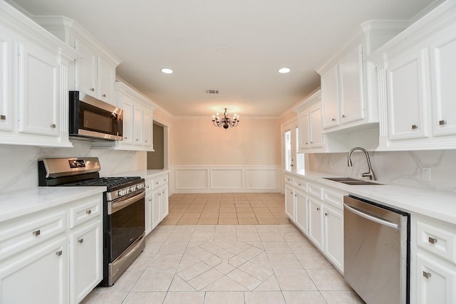 44 Farrell St, Houston, TX 77022 - kitchen featuring stainless steel appliances, a sink, a chandelier, a decorative wall, and white cabinets